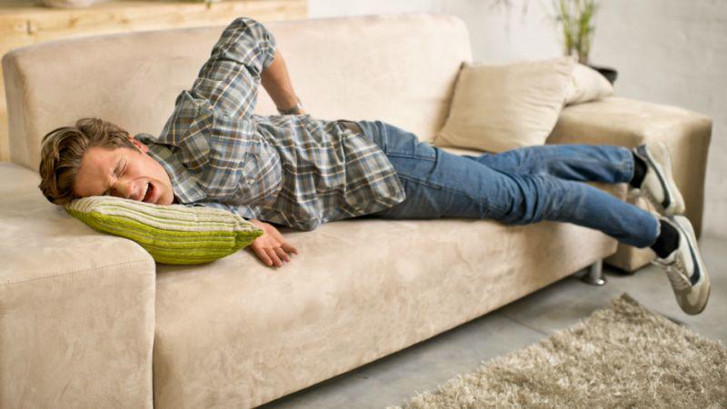 Homme qui soufre d'arthrose sur son canapé en hiver