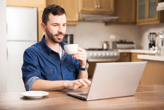 Télétravail avantages : homme buvant son café à la maison en travaillant
